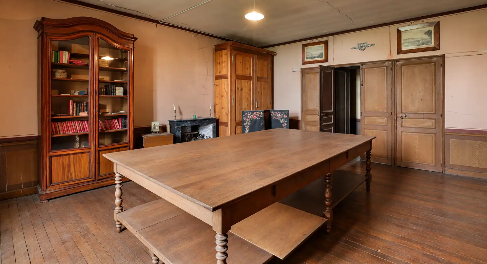 Pièce boisée avec longue table, bancs, bibliothèque vitrée et fauteuils de cuir