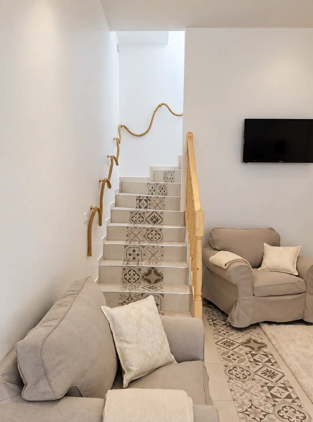 Escalier à contremarches en carreaux de ciment et rampe en bois, vu depuis le canapé du Bon Espoir