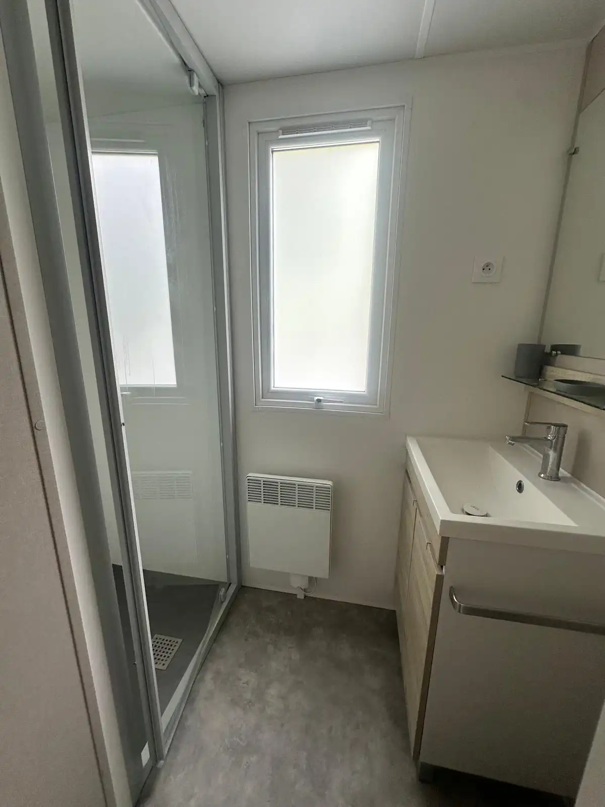 Cabine de douche, radiateur et vasque de la salle de bains du Bungalow