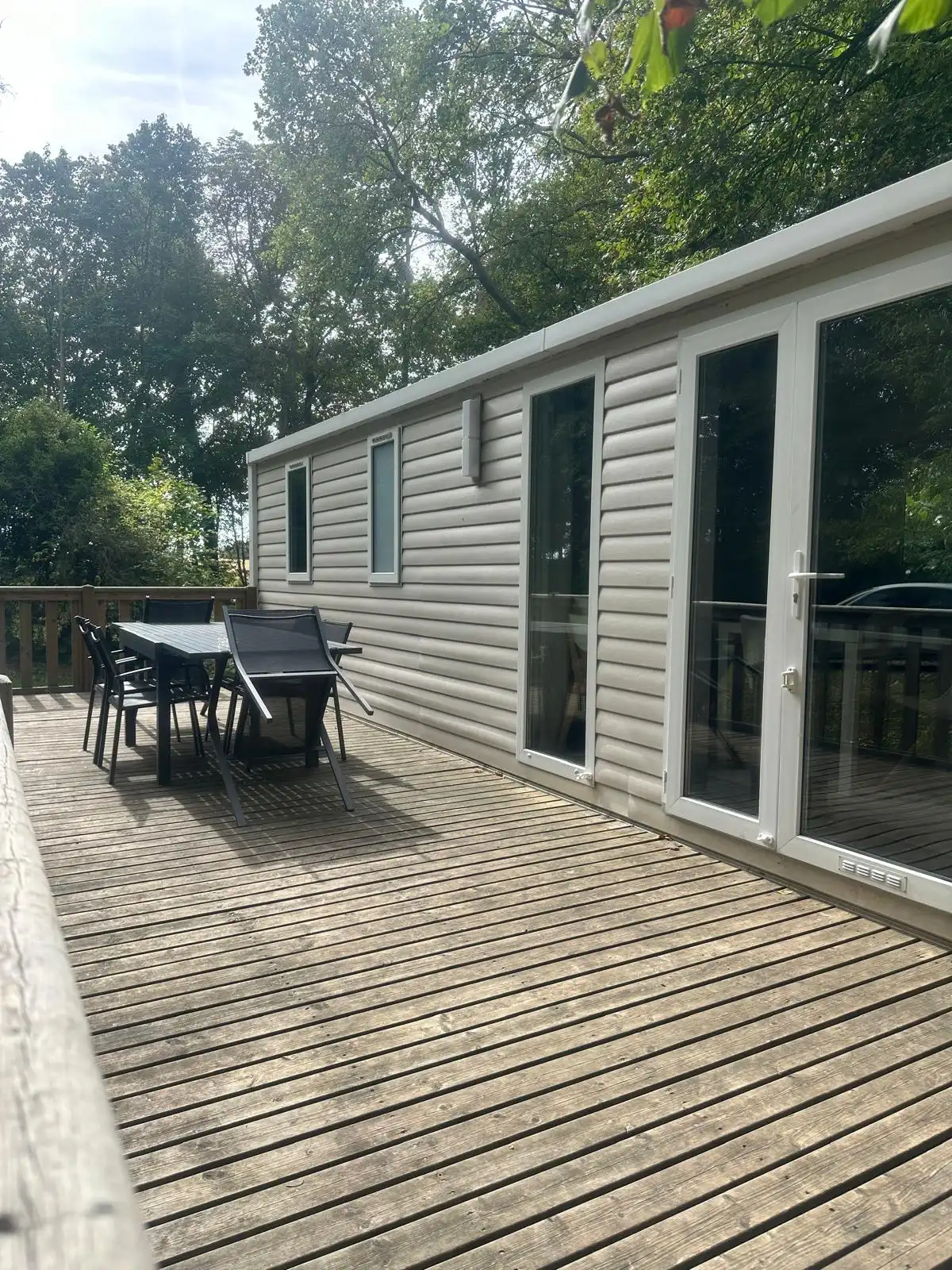 Terrasse en bois du Bungalow ouverte sur la pelouse et les arbres du parc