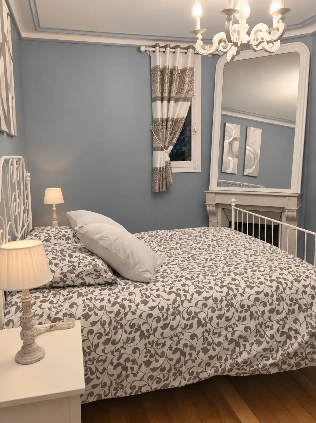 Chambre bleue du Gardien avec lit double, lustre et grand miroir au-dessus de la cheminée