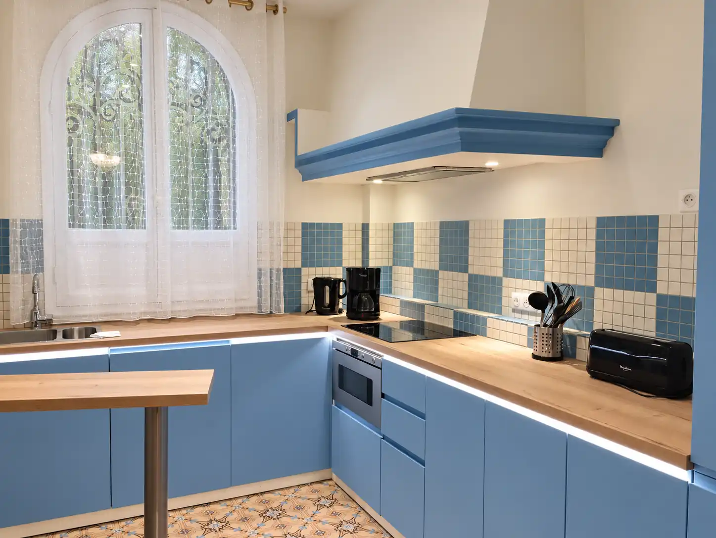 Cuisine bleue et bois du Gardien, avec crédence en carreaux et fenêtre en arc