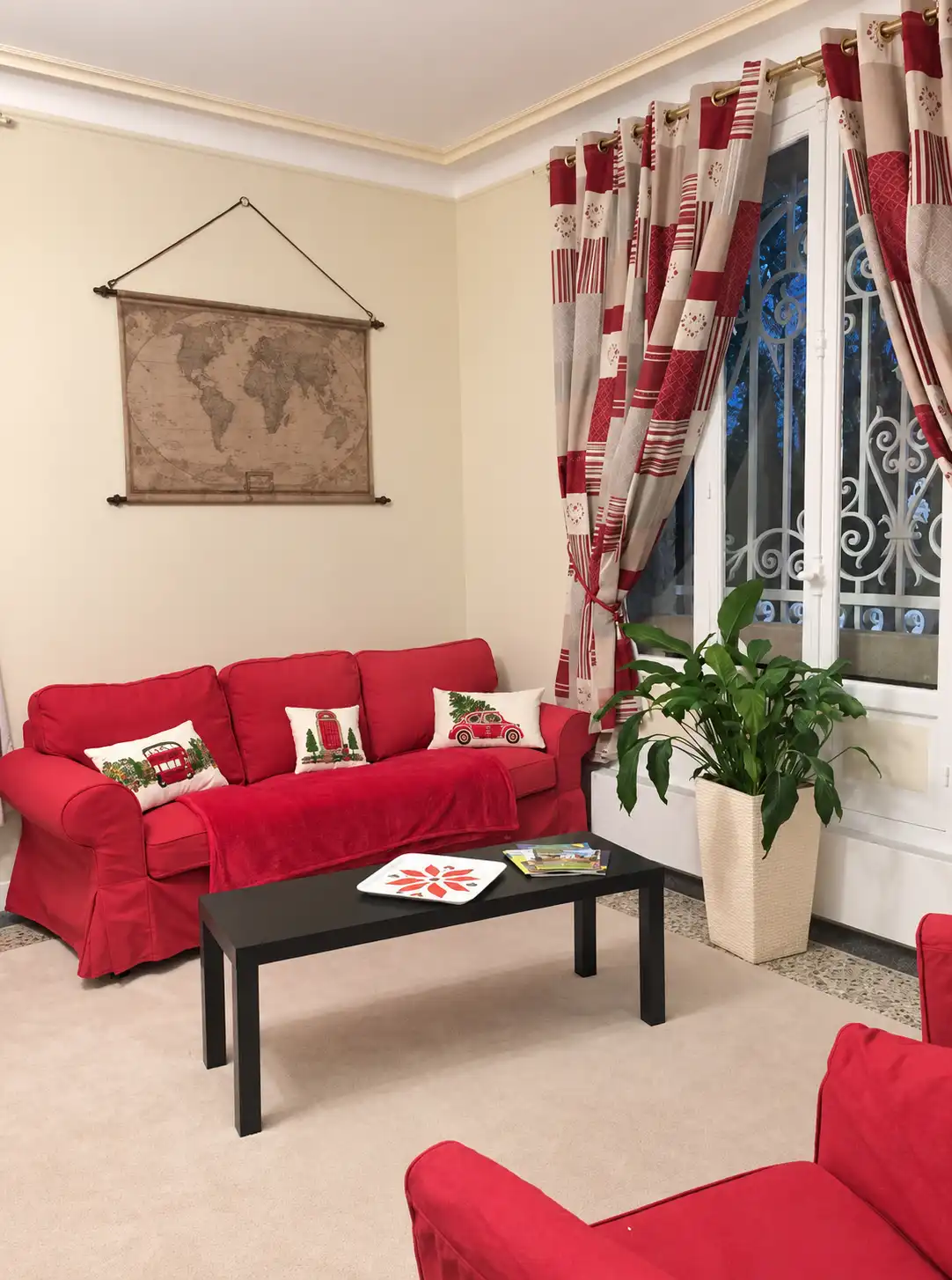 Salon du Gardien avec canapés rouges, table basse noire et carte du monde au mur