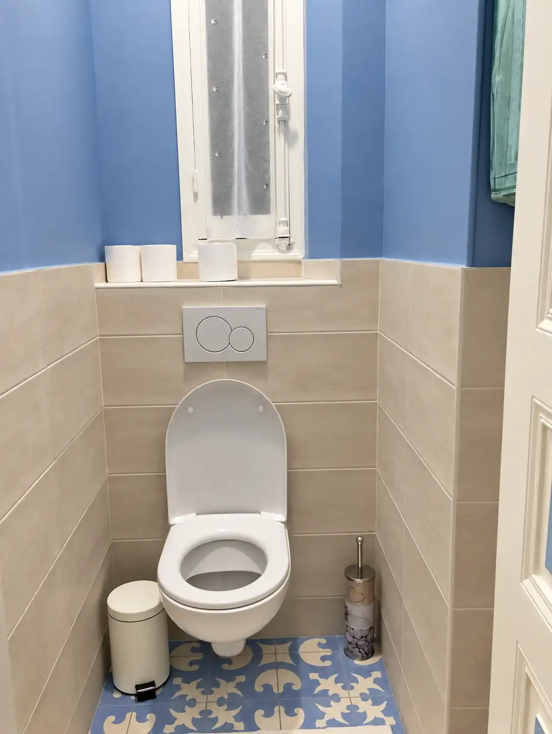 WC suspendu aux murs bleus et carrelage beige au Gardien