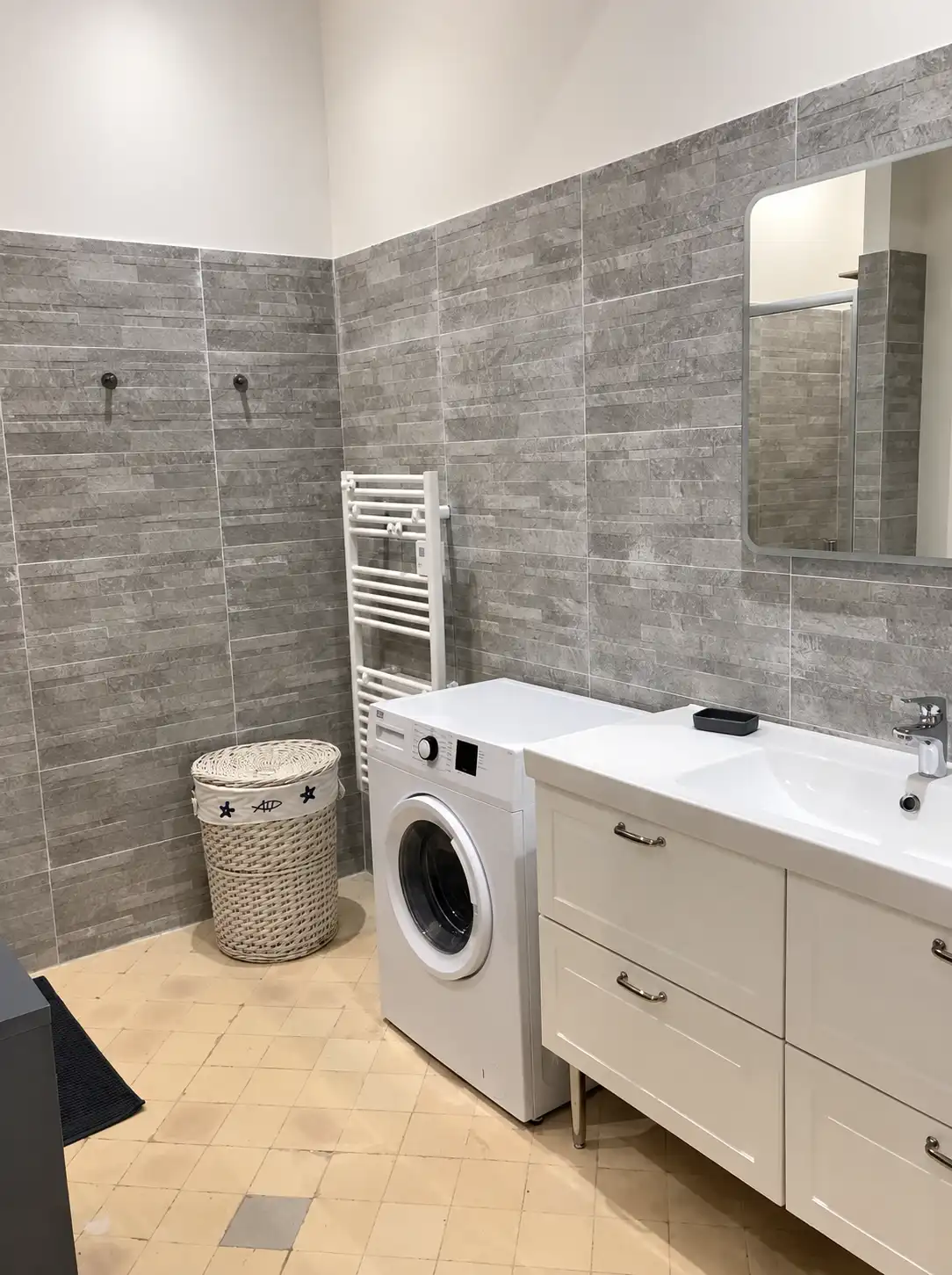 Lave-linge, meuble vasque et sèche-serviettes dans la buanderie carrelée du Monarque
