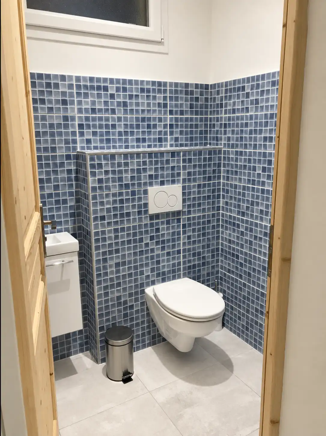 WC suspendu entouré de mosaïque bleue avec petit lave-mains au Monarque