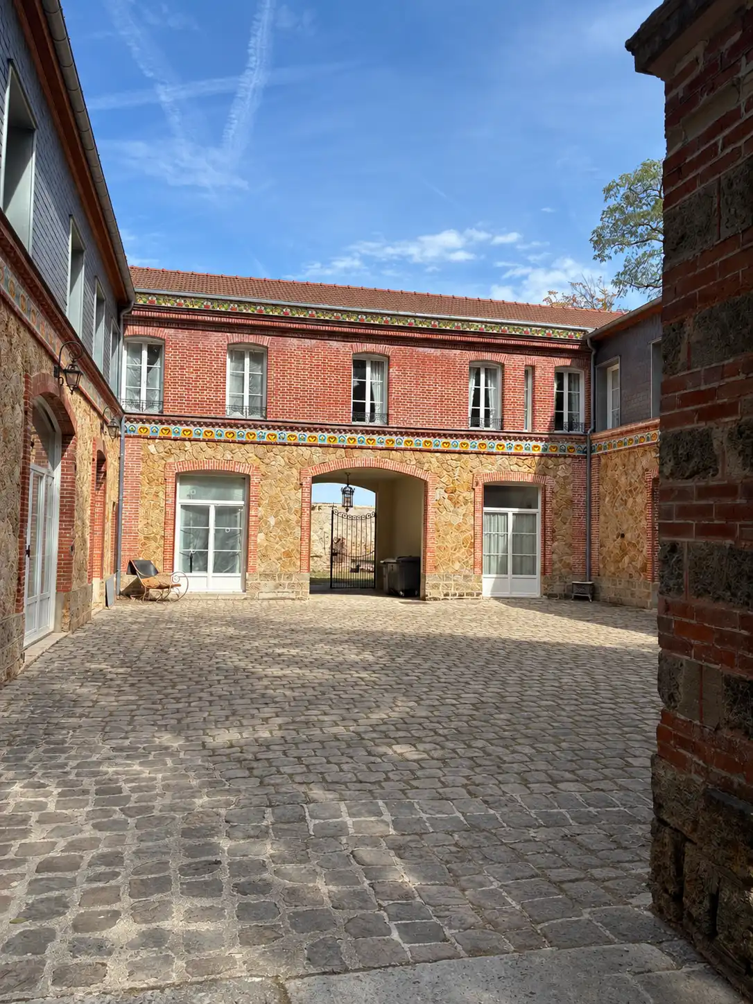 Cour pavée et façade en brique à frise décorative des communs